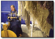 Anna Kinney, the owner of Mule Shoe Products, of Farmington, spins yarn to be used in the creation of hand-woven shawls, pictured at right.