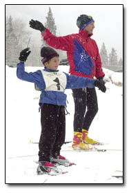 Pam Bates helps young Nordic skier, 7-year-old Ansel Chiavonne, stretch to warm up.