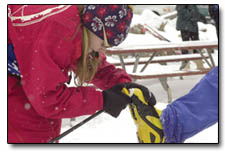 Erin Casey, 12, helps a friend with snow stuck in her boot.