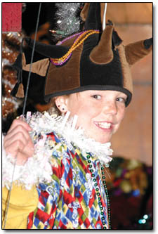 A young jester hangs onto the back of her float as the parade heads north up Main Avenue.