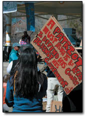 Corri Vigil, of Mancos, holds a sign displaying a quote from Edward Abbey as she listens to speeches at the pre-march rally held at Rotary Park.