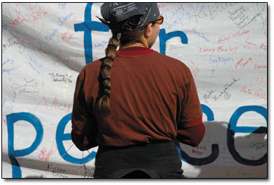 Stevonna Chavez looks for a name on the community peace banner in Rotary Park.