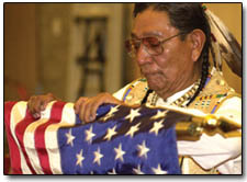 Austin Box rolls up an American flag following a Hozhoni Days prayer ceremony Friday.