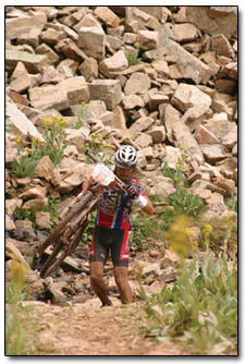 Men's pro winner Bart Bowen carries his bike over a creek crossing late Saturday afternoon.