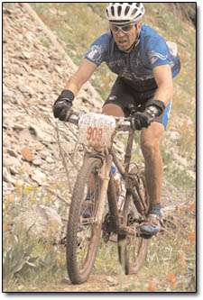 A mud-caked Mike Hogan, who took third, powers his way though one of the final ascents of the day.