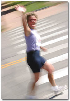 A runner gives an enthusiastic wave as she approaches the marathon finish line in downtown Durango.