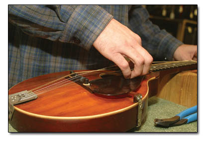 Anders Beck works diligently at restringing an antique instrument at Canyon Music Woodworks.