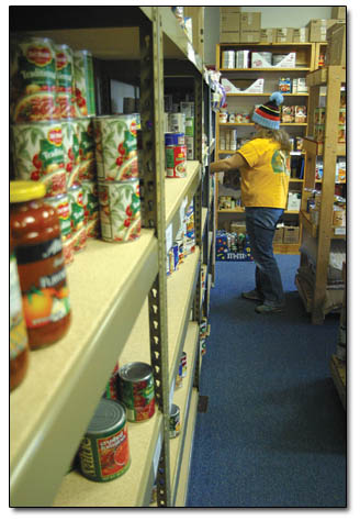 Becky Young, daughter of Durango Food Bank Directory Renea Young, helps replenish an aisle of canned goods.