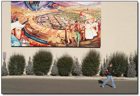 The ink-on-vinyl "reCollections" mural by lead artist Judith F. Baca dwarfs people along East Second Avenue.