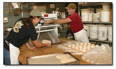 Aaron Seitz, left, and "Arch," right, put a batch of flatbread though the sheeter early Tuesday morning at Carvers.