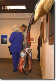 Participating artist Gina Kelly and her husband, Like, meander through the show behind a hand-carved saddle titled "Navajo Trail" by Lisa and Loren Skyhorse.