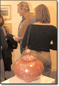 A group converses behind a salt-fumed raku ceramic bowl by Louden Kiracofe titled "Slickrock Patina."
