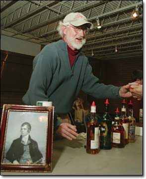 Robert Winslow serves up a shot of Scotch from behind a picture of Robert Burns, the man of the night.