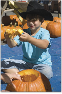 Quinn Hoover, 5, picks up a slimy section of pumpkin during a carving session Saturday.