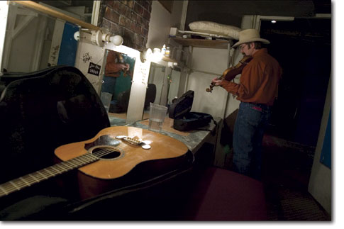 Fiddler Ken Mikell practices backstage before playing a piece with his partner Lyn Mikell at the Diamond Circle Theatre.