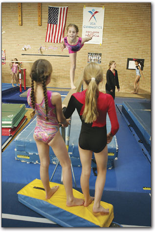 Clair Kairallo, 10, works defies gravity on the balance beam at the beginning of practice.