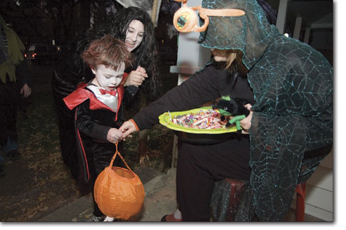 Jedidiah DeRuyter hands out candy to a very scary Aiden Strain dressed up as Dracula for the evening's Halloween festivities.