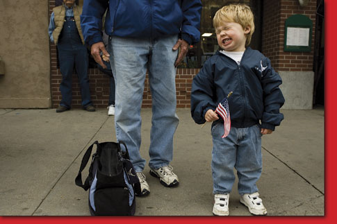 Ian McCarthy, 2, smiles for the camera as he waves his stars and stripes while his father, Jim McCarthy, stands by his side.
