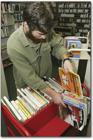 Dan Goldman begins the perpetual task of restacking books near the front desk of the library.