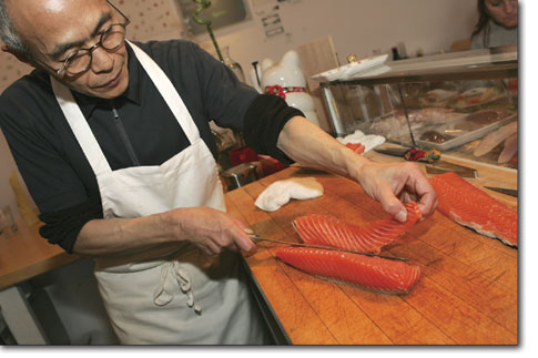 Sushi chef Koko Mizuno precisely slices a salmon filet at the Sushitarian.