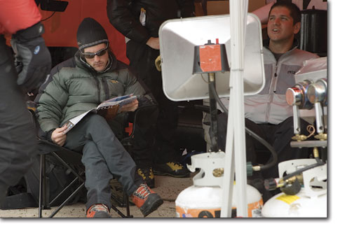 Eric Wynn catches up on the latest issue ofRock & Iceas he stays warm next to a heater Sunday.