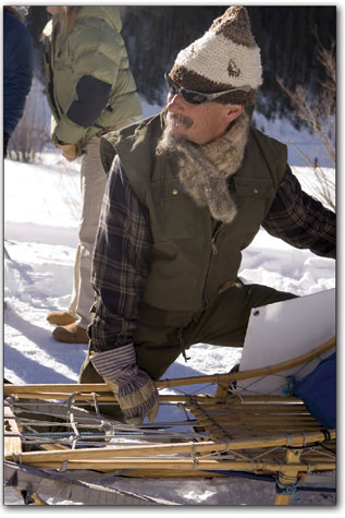 Fred Canfield helps hold a sled for a musher as the racer gets
ready to start the day's competition.