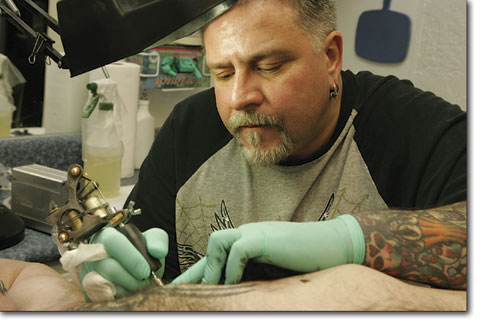 Bob Lyon, of Blue Tiger Tattoo, concentrates on the work in
front of him from his well lit work station.