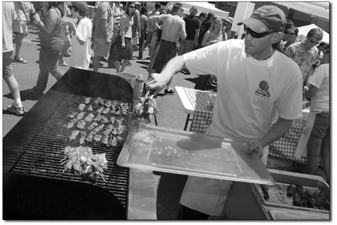 Mick Roth, of East by Southwest, works the grill on a hot Sunday
afternoon as a steady line of customers eagerly await food.