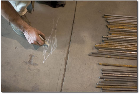 Left:Rod Pickett scribbles an illustration on the floor of what
the tips of dozens of pieces of steel will look like when
complete.