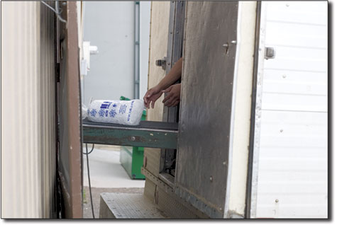 Bag after bag of ice moves along a conveyer belt. The ice is
neatly stacked inside a freezer truck before delivery.