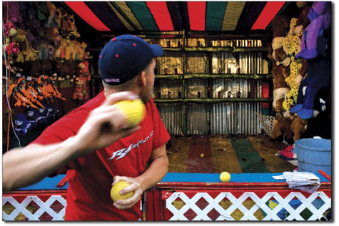 Jason Sorrells loads a pitch while playing the Bottle Break game  at the fair on Saturday.