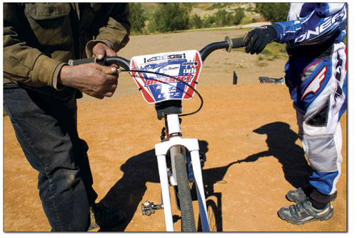 A parent adjusts the brakes of a racers bike.