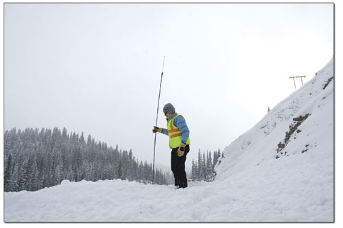 Avalanche forecaster Susan Hale uses an avalanche probe to
mesure the center-line depth of a slide that crossed Highway 550
during a recent control mission.