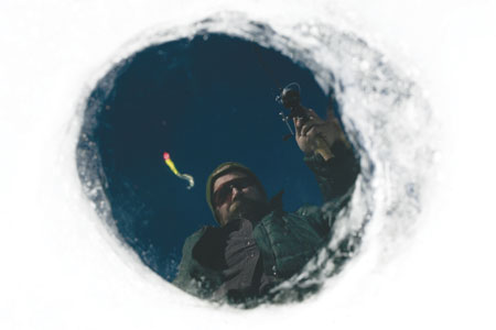 C.W. Aton peers into a hole in the ice while lowering his lure
into the water at Pastorius Reservoir this week.