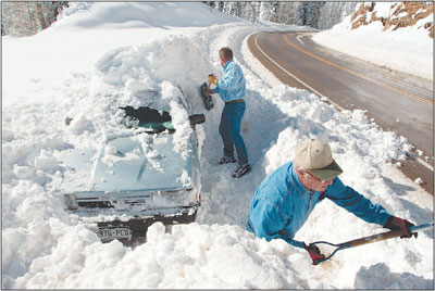 Keith Richardson, bottom right, and David Hilgenfeld, of Grand
Junction, dig a Subaru out of a day-and-a-halfs worth of snow and
plow pack early Sunday morning, just north of Cascade Creek. Keith
was forced to abandon the car on Friday night as road conditions
became too treacherous.