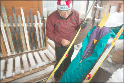 Mel Mathis gets some kick going as he carefully waxes a pair of
skis on opening day.