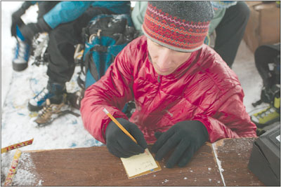 Kevin Sainio, with Backcountry Experience, jots down some notes
while fitting people with crampons, axes and helmets Saturday
morning before the descent into Cascade Canyon.