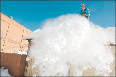 Jim Weller pushes a load of snow off of the roof of his shed in
the alley between Greene and Reese streets.