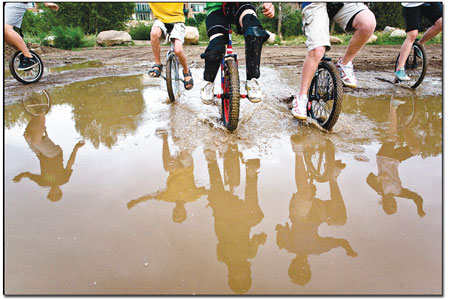 Several riders plow their way through a mud puddle.