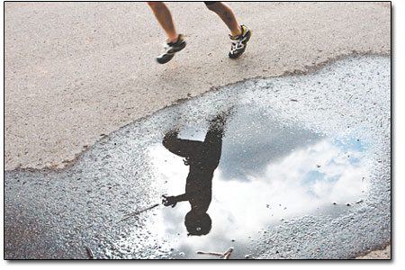 A runner is reflected in a puddle as he makes his way to the
finish.