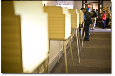 Empty voting stations sit aglow as a gentleman fills in his
ballot between voter ssurges.