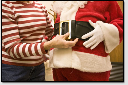 Mrs. Claus helps tighten Santas belt around his bulging belly,
pre-game, in the malls dressing room.