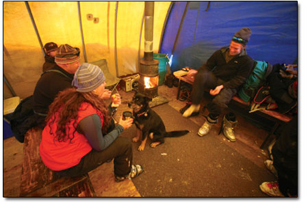 A group of ski partners boot up by a hot fire in the Powder Cats
base area tent