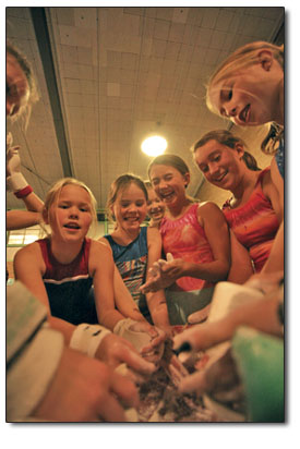 The girls intermediate class enjoys a lively chalk-up before
practice on the bars.