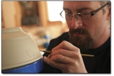 Potter Adam Field etches away on raw wares in his back yard studio.