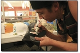 Artist Bryan Raymond Simmons adds a finishing touch to a hat in the commons area of the Student Union.