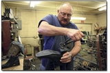 Corky McIntyre pulls the rubber sole from the heal of a leather boot.
